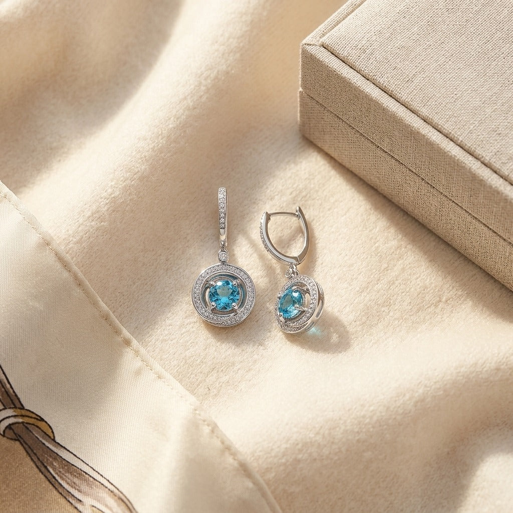 Blue Topaz and Diamond Swirl Dangling Earrings in 14k White Gold (6mm) — textile flat lay