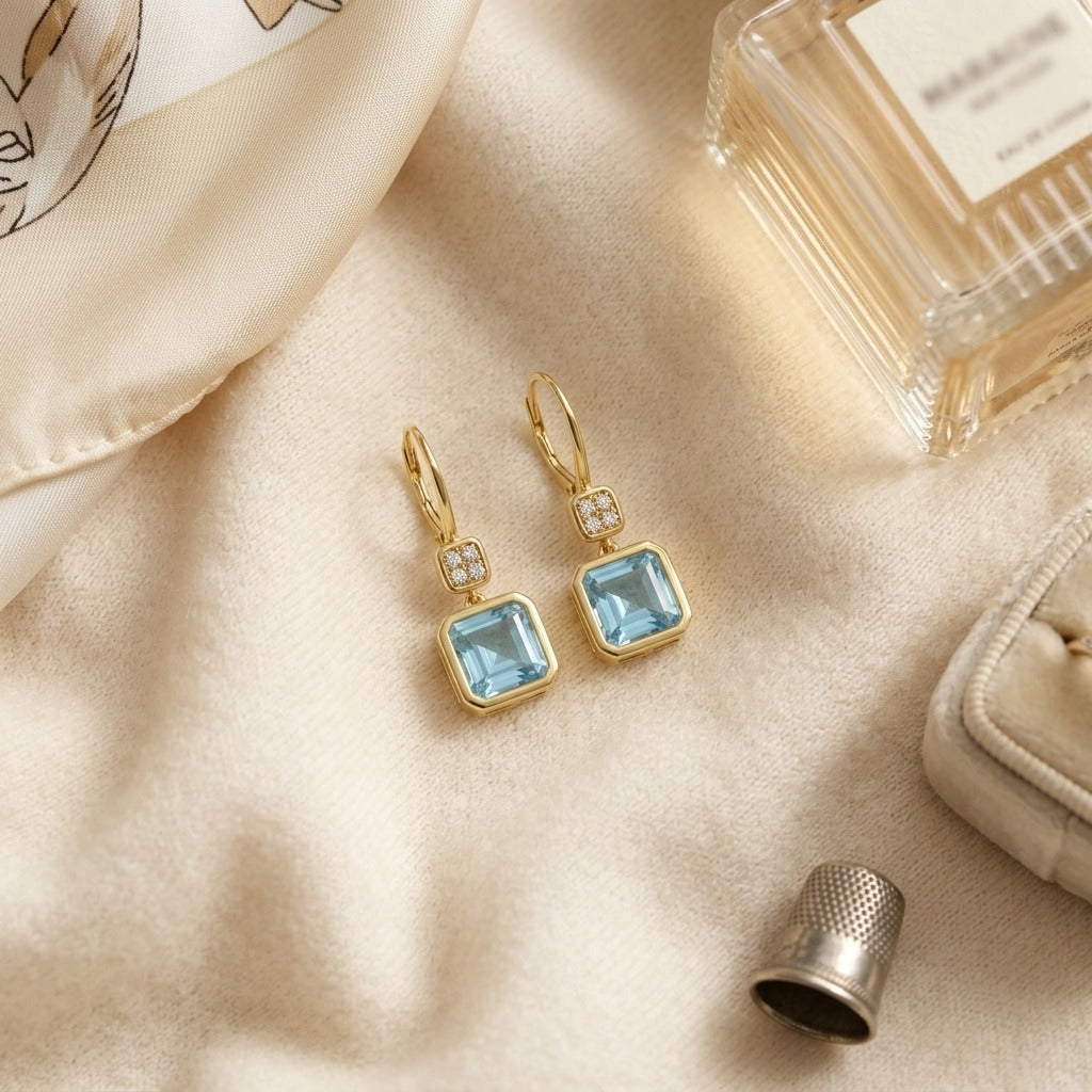 Swiss Blue Topaz Bezel Earrings in 14k Yellow Gold 0.08ctw — textile flat lay