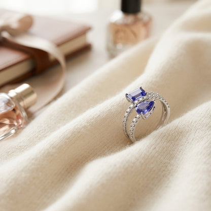 Tanzanite Pear and Emerald Cut Ring with Pave Split Shank in 14k White Gold — textile flat lay