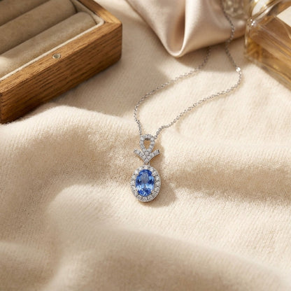 Sapphire Oval and Pave Diamond Halo Pendant in 14k White Gold — textile flat lay