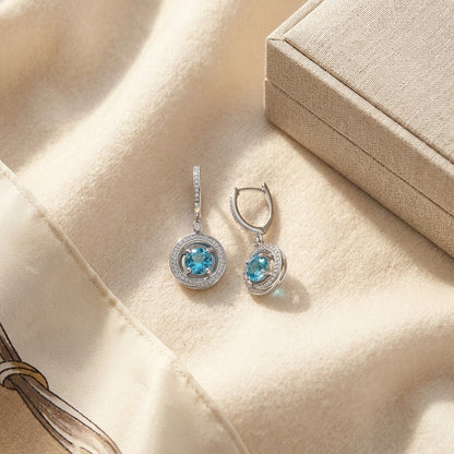 Blue Topaz and Diamond Swirl Dangling Earrings in 14k White Gold (6mm) — textile flat lay