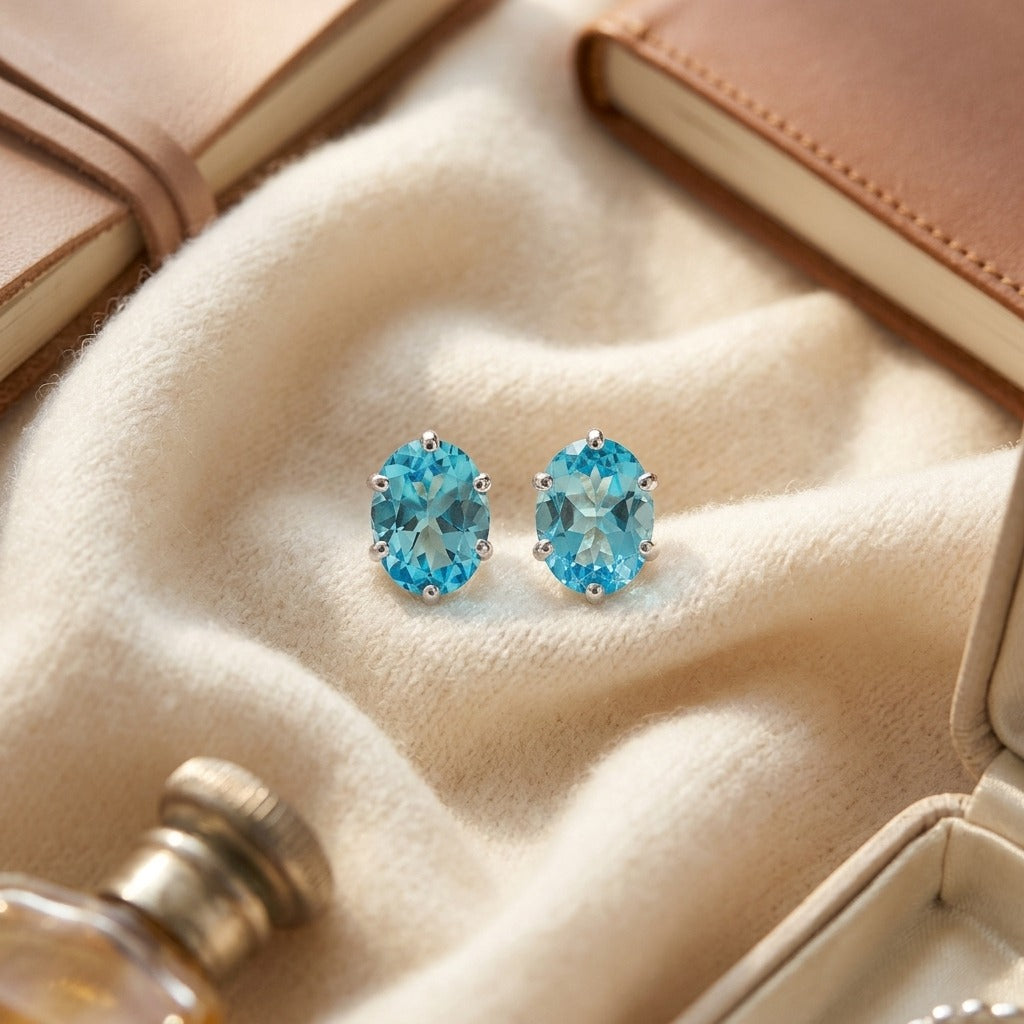 Blue Topaz Oval Stud Earrings in 14k White Gold (8x6mm) — textile flat lay