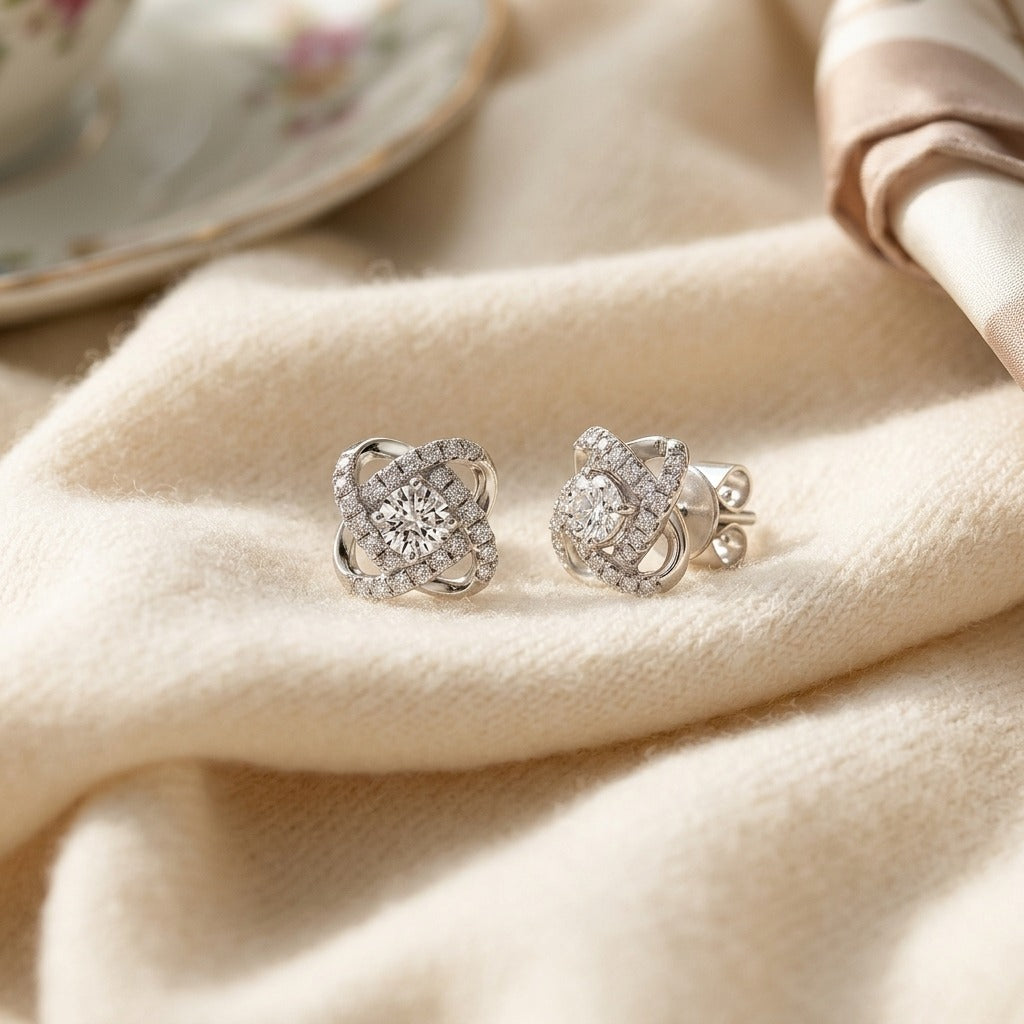 Diamond Pave Cross Knot Earrings with Round Centers in 14k White Gold — textile flat lay