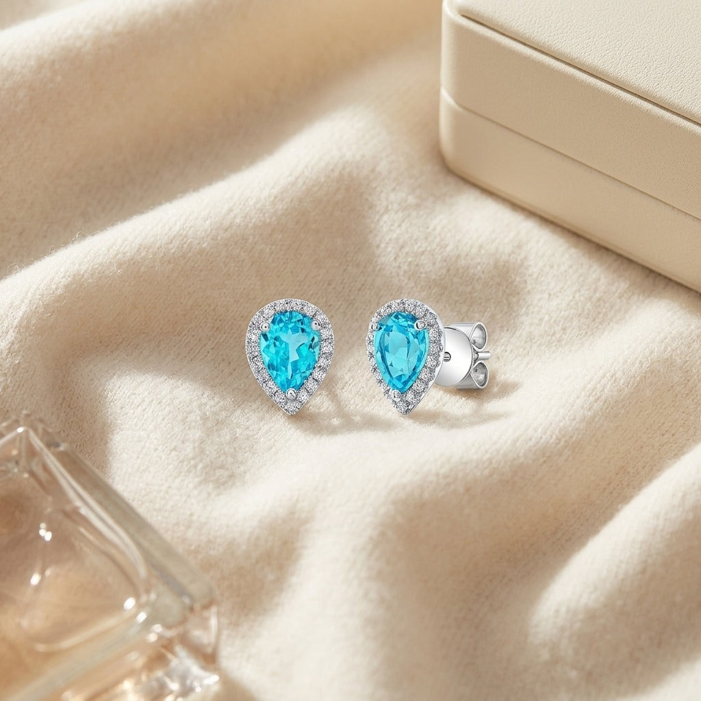 Blue Topaz and Diamond Halo Teardrop Earrings in 14k White Gold 0.18ctw — textile flat lay