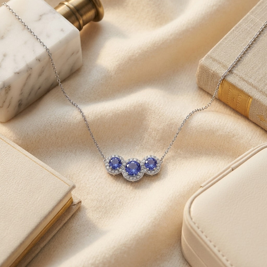 Tanzanite and Diamond Round Halo Trio Necklace in 14k White Gold — textile flat lay