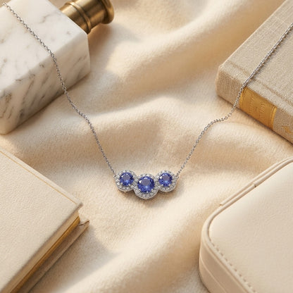 Tanzanite and Diamond Round Halo Trio Necklace in 14k White Gold — textile flat lay