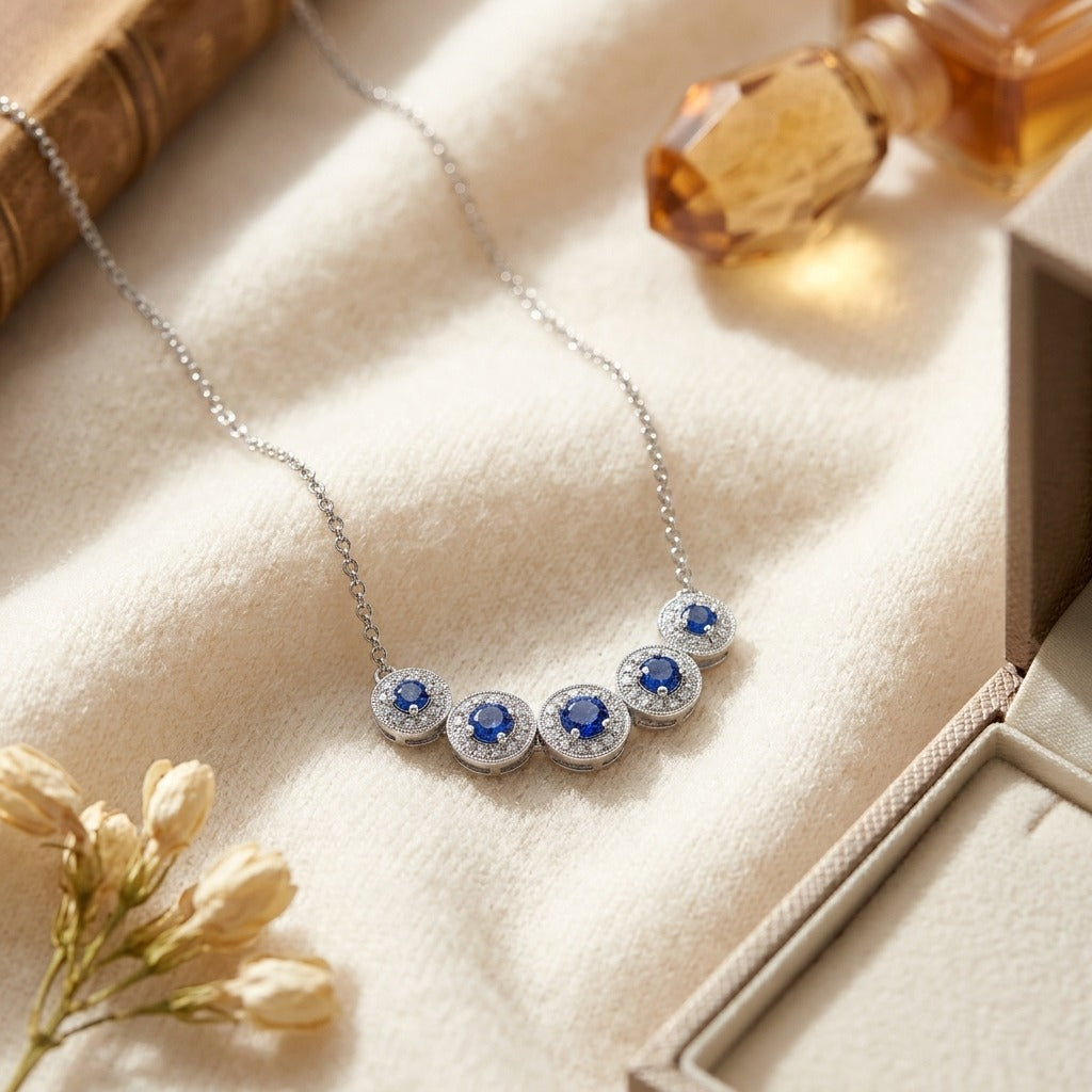 Sapphire and Diamond Five Section Graduated Halo Curved Necklace in 14k White Gold — textile flat lay
