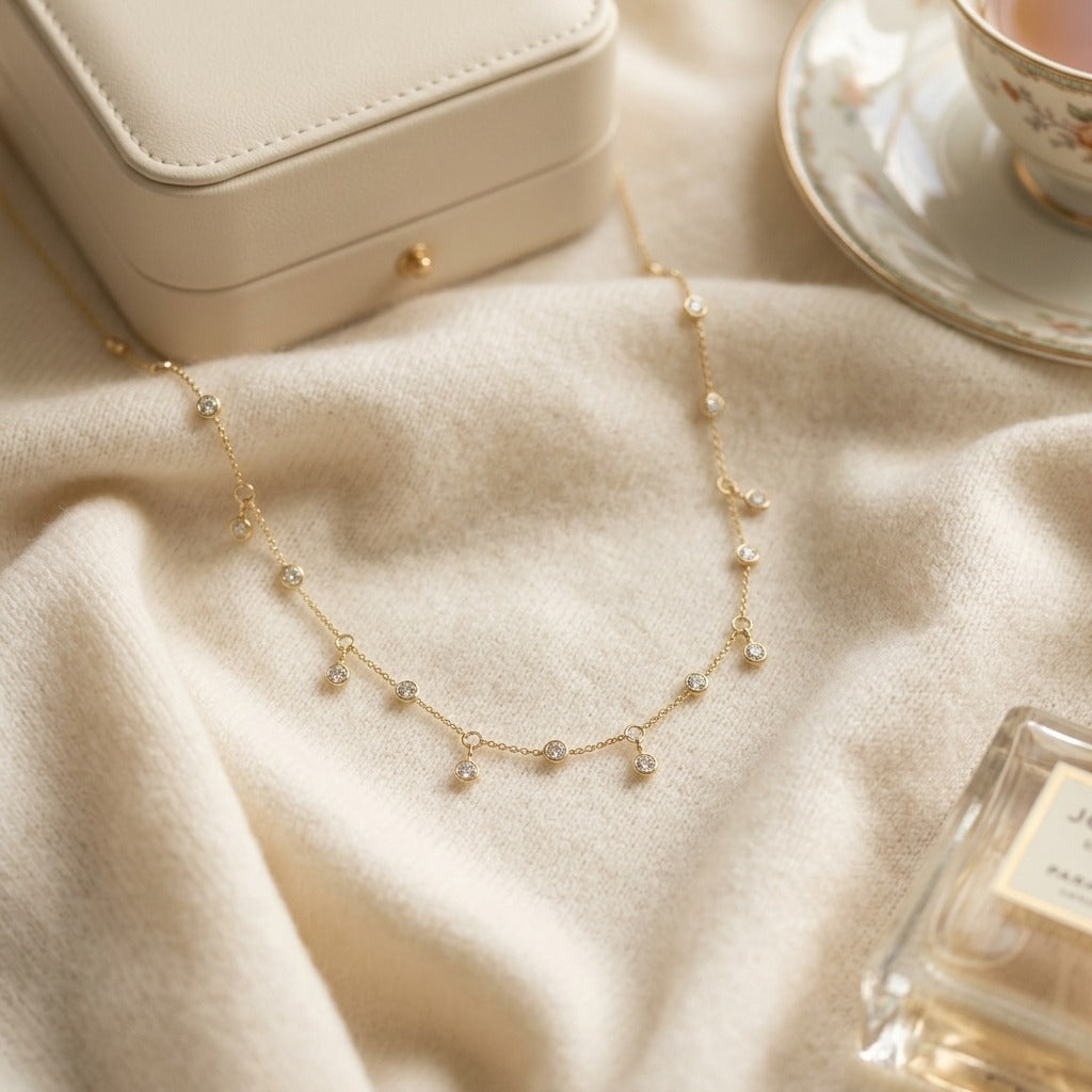 Diamond Station Necklace with Fixed and Dangling Bezels in 14k Yellow Gold — textile flat lay